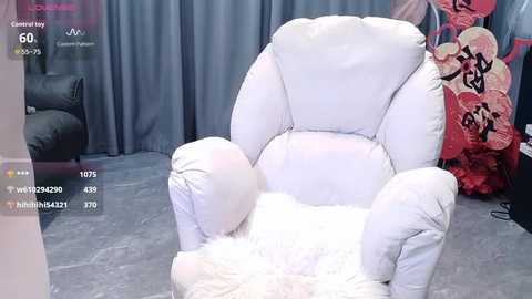 Media: Video of a white, fluffy armchair in a room with grey curtains, red and white decorative pillows, and a soft rug.