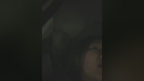 A dimly lit video captures a close-up of a person with curly hair, partially obscured by shadow, suggesting a somber or intimate moment.