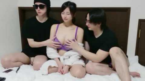 Video of an Asian woman in purple lingerie being fondled by two Asian men in black shirts on a bed with white sheets.