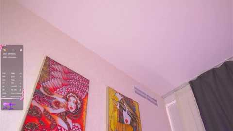 A video of a minimalist room with a white ceiling, featuring two vibrant, colorful paintings of Asian women in traditional attire on the beige walls. A dark curtain and an air vent are visible.