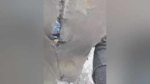 A video shows a man wearing a blue and black jacket, standing amidst heavy smoke and debris, possibly after an explosion. The background is hazy and gray.
