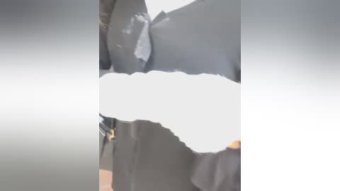 A video of a person's upper body, with a dark shirt and partially obscured face. The background is blurred, and the person's hair is visible, suggesting a casual, indoor setting.