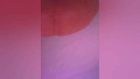Video of a close-up, blurred human face with visible lips and nose, set against a gradient background transitioning from red to pink. The image is soft and abstract, lacking distinct features, conveying a dreamy, almost surreal atmosphere.