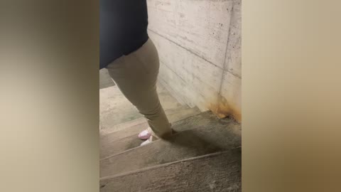 A video shows a person in beige pants stepping on a wet concrete floor, with a puddle of water and a yellow stain visible. The person is wearing a dark shirt.