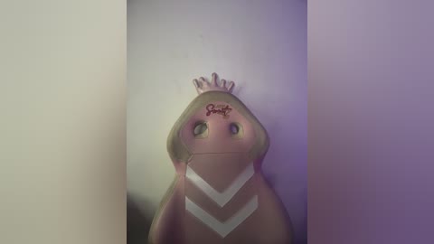 A digital video of a plush toy resembling a rabbit with a pink face, white zigzag markings, and a crown. The background is a gradient of soft purples and pinks.