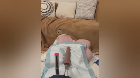 Video of a cozy living room with a plush brown sofa, beige cushions, and a white blanket. A small teddy bear and a pink lipstick are on the sofa.