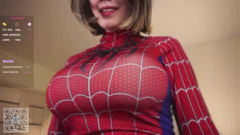 Video of a woman in a tight, red Spider-Man suit, emphasizing large breasts. Background shows a bathroom with a white wall and a QR code.