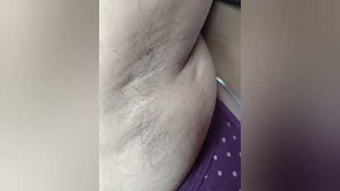 A close-up video of a person's abdomen and lower back, showing light skin with natural hair and a purple polka-dotted underwear. The background is blurred.