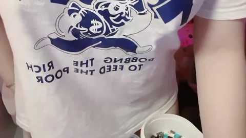 Video of a white person wearing a white T-shirt with blue cartoon dog logo and text \"RUN FOR THE DOG FOUNDATION.\" Person holds a white cup with blue and white dog design.