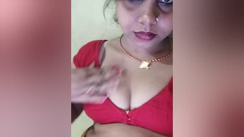 Media: A video of a South Asian woman with light brown skin, wearing a red bra, gold necklace, and a nose ring. Her breasts are prominent, and she has a sensual expression.