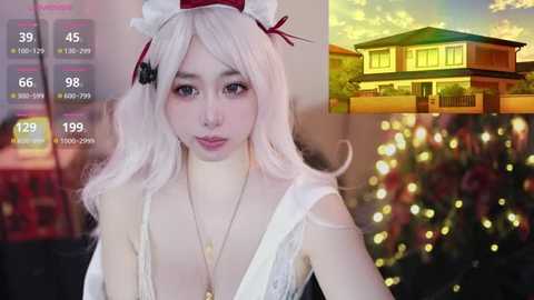 Video collage: top, a young woman with fair skin, long white hair, wearing a white lingerie outfit; bottom left, a cozy room with a fireplace; bottom right, a lit Christmas tree and a house.