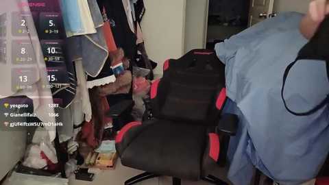 Video of a messy room with a black gaming chair, clothes hanging, scattered items, and a blue shirt draped over the chair.
