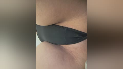 Video of a woman's lower torso in black underwear, showcasing smooth skin and slight stretch marks, with a blurred, neutral-colored background.
