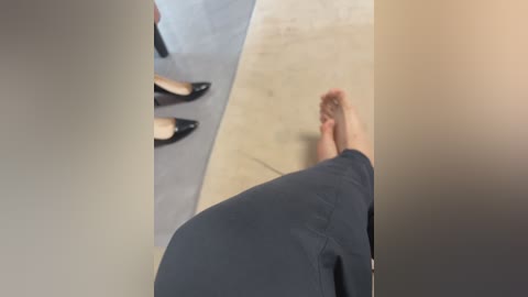 Media: A video captures a man in black pants and black shoes, with a light-colored foot, standing in a mirrored room. The image is slightly blurry, focusing on the reflection and the man's legs.