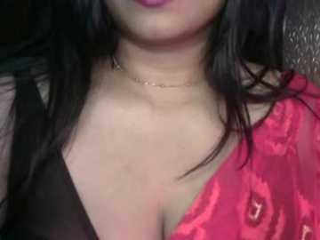 Video of a woman with medium skin tone, wearing a red and black floral-patterned sari, featuring a gold necklace, and black hair.