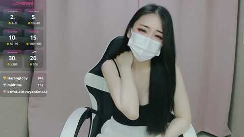 Media: Video of an East Asian woman with long black hair, wearing a black-and-white maid uniform, mask, and seated on a gaming chair. Background shows streaming app interface with statistics.