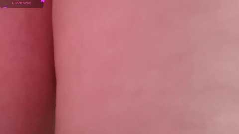 Media: A close-up video of a smooth, pale pink buttock, with a faint vertical line running down the center, likely from a crease. The background is blurred, emphasizing the skin texture.