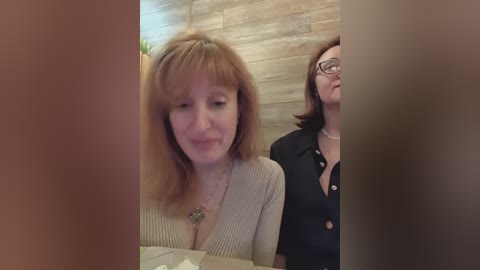 Media: A video of two women in a restaurant. One has shoulder-length brown hair, a V-neck sweater, and a necklace; the other has short brown hair, glasses, and a black blouse.