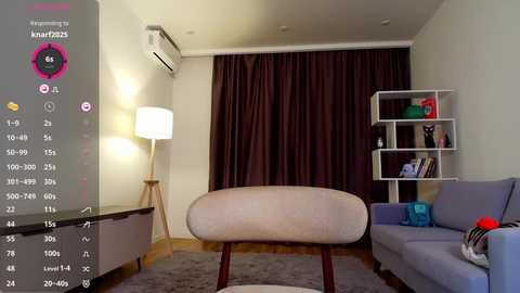 Media: Video of a modern, minimalist living room with beige chair, gray sofa, white shelving unit, dark curtains, wooden floor, and a tall floor lamp.
