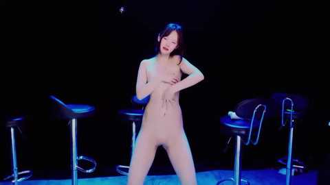 Media: Video of a nude East Asian woman with small breasts, medium build, and brown hair, standing center stage against a black backdrop, flanked by bar stools.