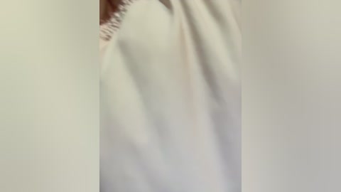 A close-up video of a person's arm in a white sleeve, blurred with a focus on the fabric's texture and the slight creases on the skin.