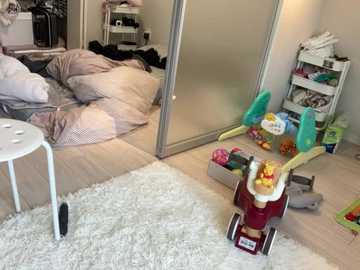 Video of a messy bedroom with a white chair, cluttered floor, a toy car, and a white wardrobe.