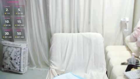 Video of a medical examination room with a draped, white examination table, a white curtain, and a wall-mounted phone. Text on the screen displays vital signs.