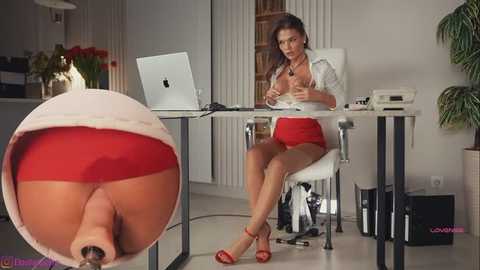 Video of a busty woman in a red blouse and skirt, seated at a desk in a modern office, with a close-up of her bare buttocks in a white, fluffy thong.