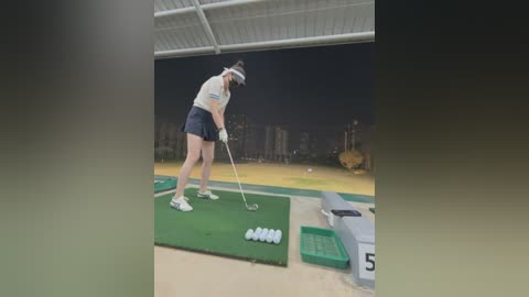 Video of a female golfer in a practice session, wearing a white visor, dark shorts, and a white shirt, hitting a golf ball on a green mat.