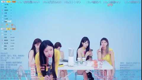 A video of a digital interface with four Asian women, each wearing a yellow shirt, sitting around a table in a bright room. The background features a blue gradient with Chinese text.
