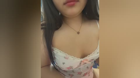 Video of an Asian woman with long black hair, wearing a white floral-patterned spaghetti strap top, showcasing her cleavage and smiling with red lipstick.