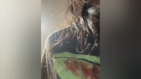 Video of a person with wet hair, wearing a colorful, patterned shirt, captured from a close, blurred perspective, with a soft, diffused lighting effect.