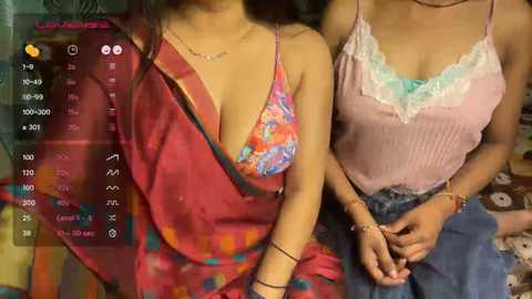 Video of two women in casual attire, one in a colorful sari and the other in a pastel top, sitting side by side.